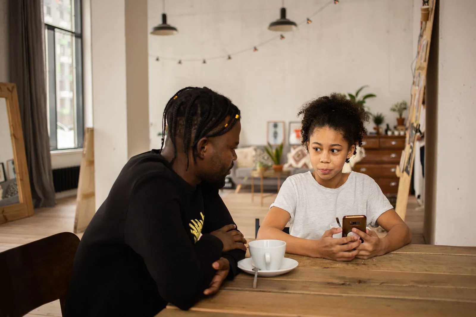 A father listening as his daughter talks about something on her phone